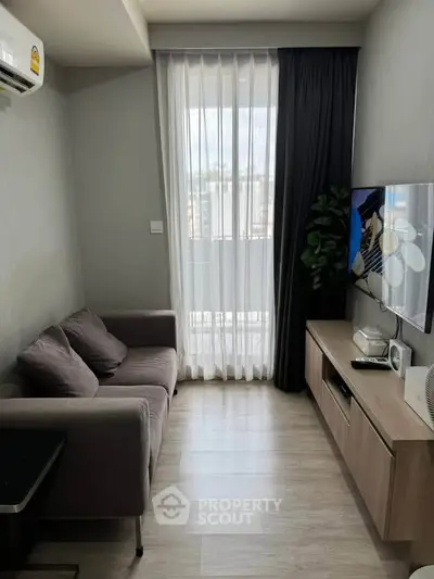 Cozy living room with modern decor and natural light, featuring a comfortable sofa and large TV.