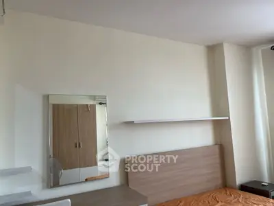 Modern bedroom with minimalist design, featuring a sleek mirror and wooden headboard.