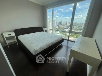 Spacious bedroom with stunning city view and modern furnishings in high-rise apartment.