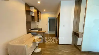 Modern studio apartment with wooden flooring and compact kitchen area, ideal for urban living.