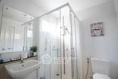 Modern bathroom with glass shower and sleek fixtures in bright white decor.