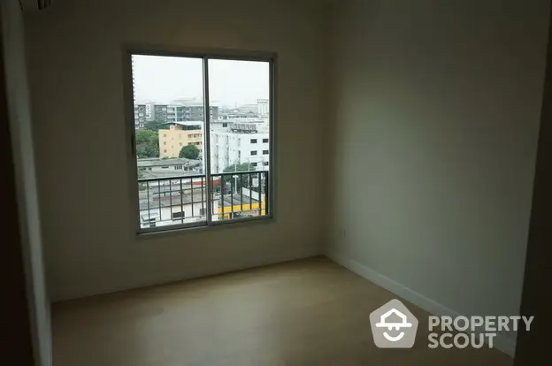 Spacious empty room with large window offering city view, perfect for customization.