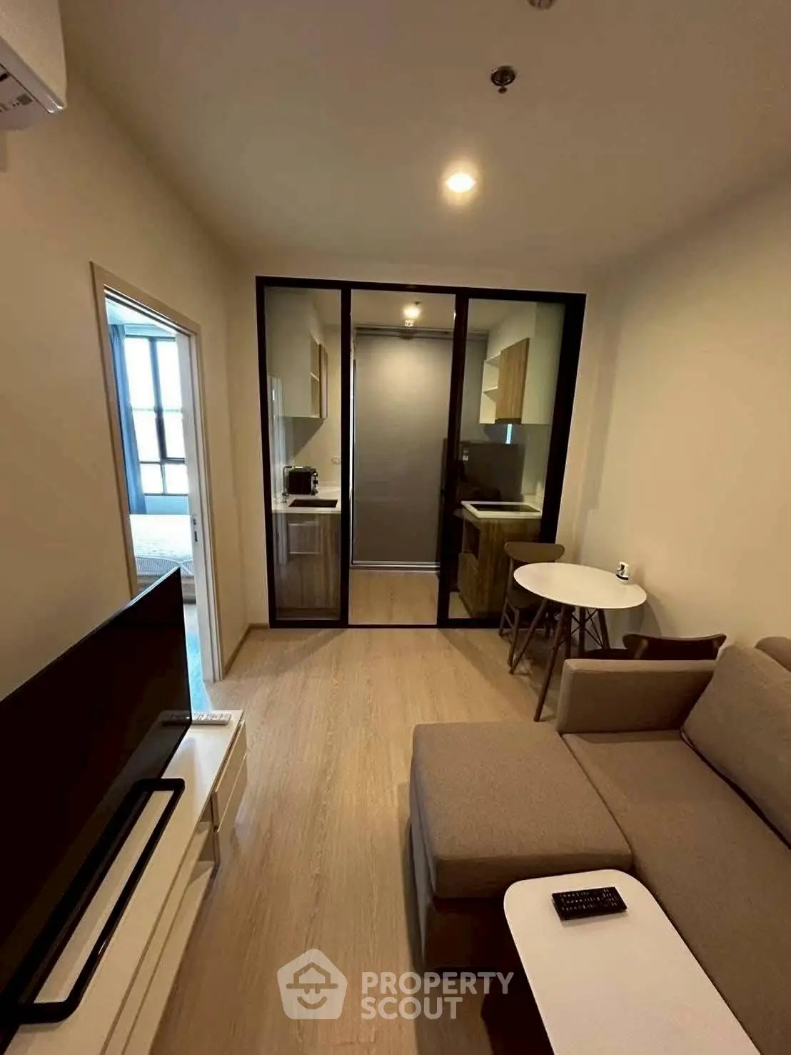 Modern living room with cozy sofa, TV, and open kitchen layout in stylish apartment.