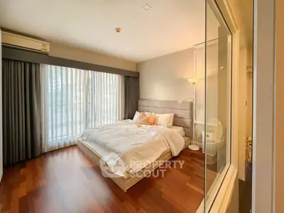 Spacious bedroom with large window and elegant wooden flooring