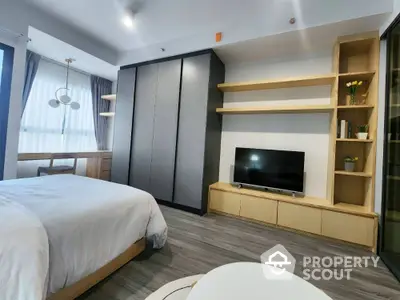 Modern bedroom with sleek design, featuring a large wardrobe, TV unit, and natural light from a window.