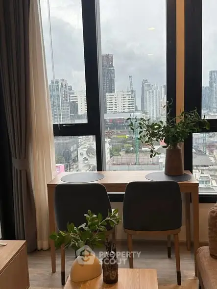 Modern apartment with city view, featuring a stylish desk and chairs by large windows.