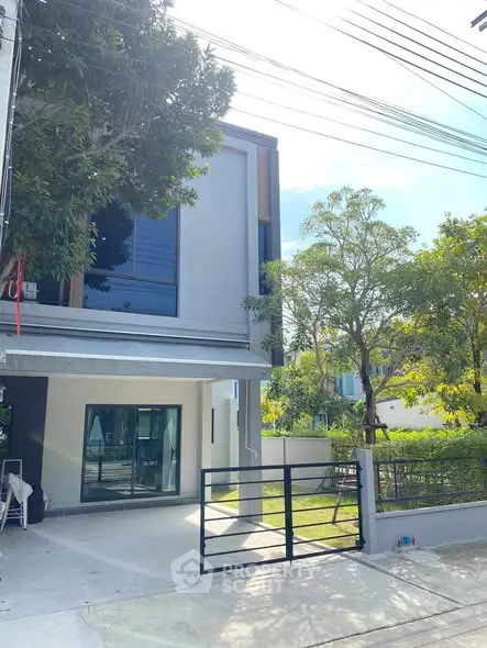 Modern two-story house with gated driveway and lush greenery
