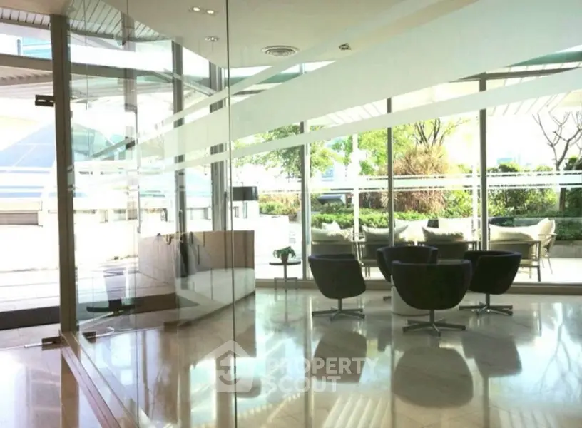 Modern office lobby with glass walls and sleek furniture, offering a bright and inviting atmosphere.
