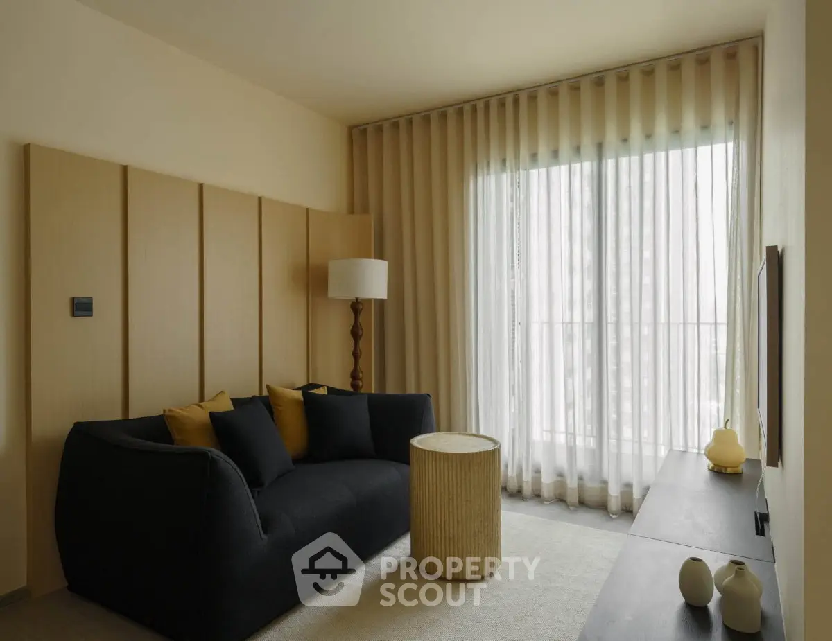 Modern living room with stylish sofa, floor lamp, and large window with sheer curtains.