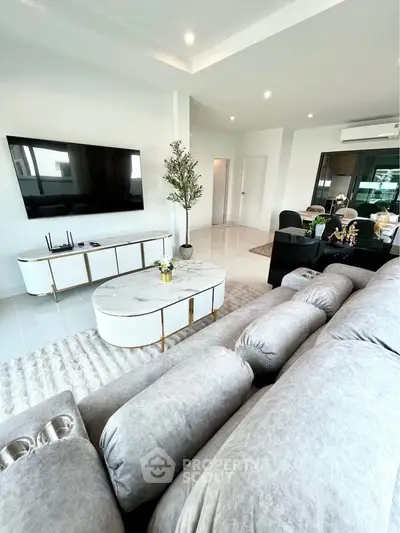 Luxurious modern living room with plush sofa and large TV, perfect for relaxation and entertainment.