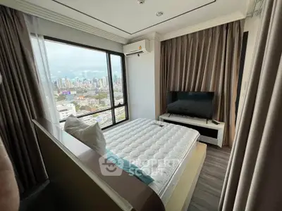 Modern bedroom with city view, featuring large window and sleek furnishings.