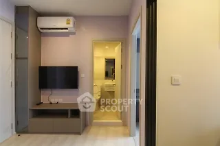 Modern apartment interior with wall-mounted TV and air conditioning, leading to a compact bathroom.
