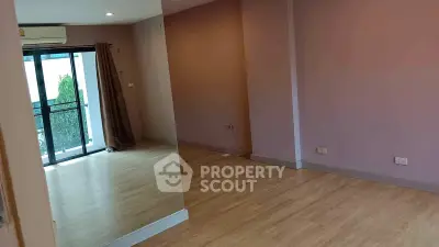 Spacious empty room with wooden flooring and balcony access in modern apartment
