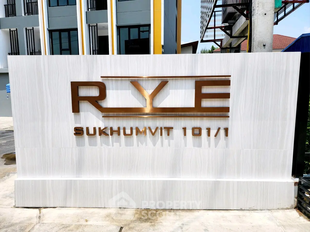 Modern building entrance sign for RYE Sukhumvit 101/1, showcasing contemporary architecture.