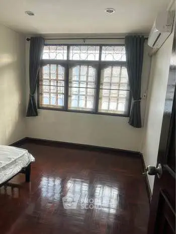 Spacious bedroom with large window and wooden flooring, perfect for natural light lovers.