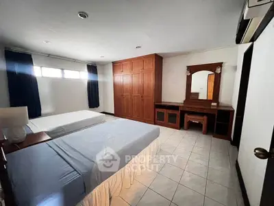 Spacious bedroom with twin beds and wooden wardrobe in a bright, airy setting.