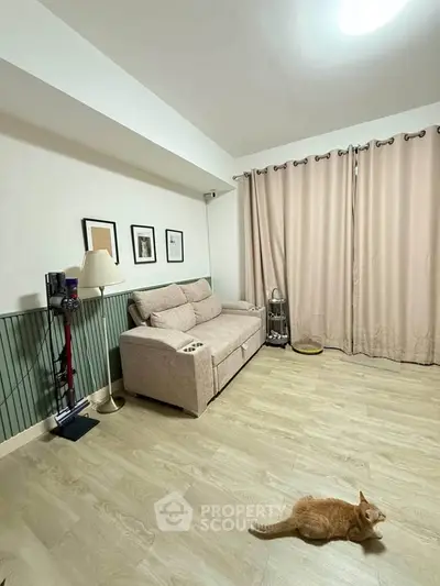 Cozy living room with stylish decor and wooden flooring, featuring a comfortable sofa and elegant curtains.