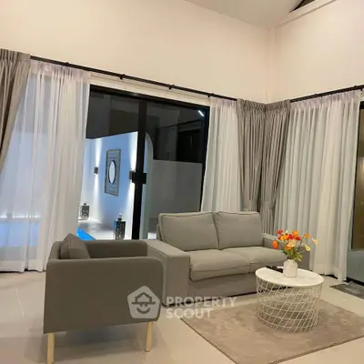 Modern living room with elegant gray furniture and pool view, perfect for relaxation.