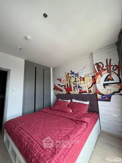 Modern bedroom with graffiti wall art and red bedding in stylish apartment.
