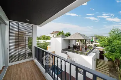 Stunning balcony view of modern villa with lush greenery and clear blue sky.