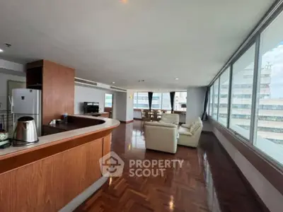 Spacious open-plan living room with panoramic city views and elegant wooden flooring.