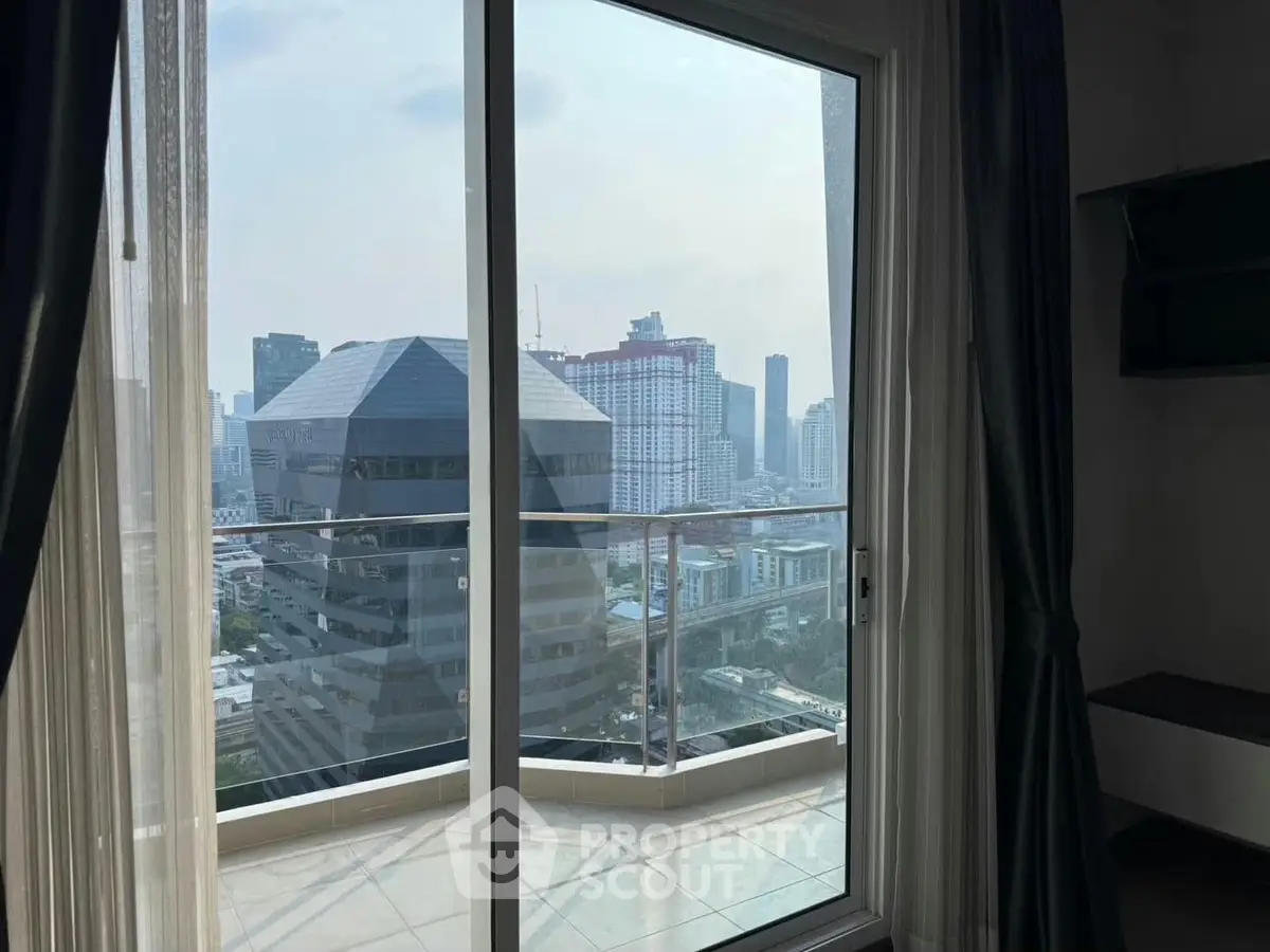 Stunning cityscape view from a high-rise apartment balcony with glass doors.