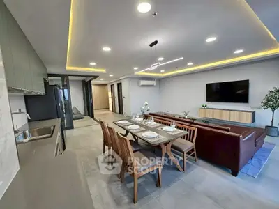 Spacious modern living room with open kitchen and elegant dining area, featuring sleek furniture and ambient lighting.