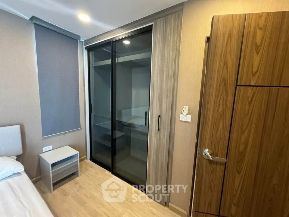 Modern bedroom with sleek sliding wardrobe and wooden flooring