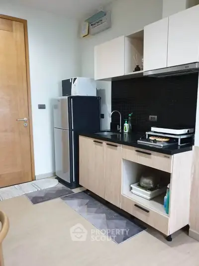 Modern kitchen with sleek cabinets and stainless steel fridge in cozy apartment.
