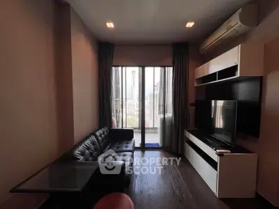 Modern living room with sleek black leather sofa, large TV, and city view through glass doors.
