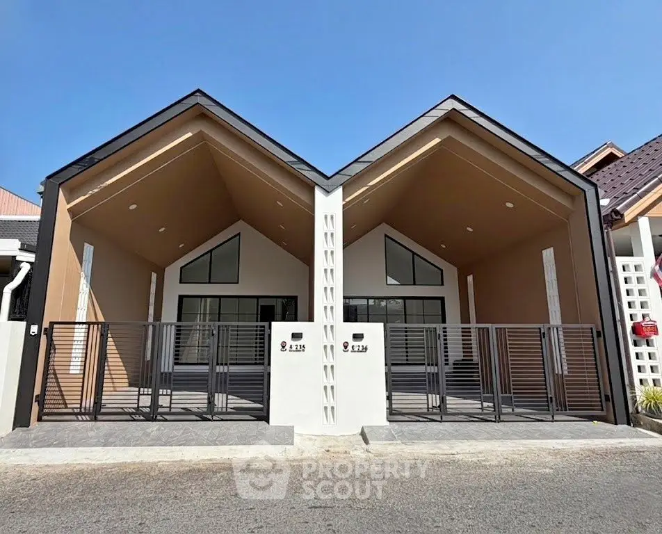 Modern twin houses with sleek design and gated entrance in a sunny neighborhood.