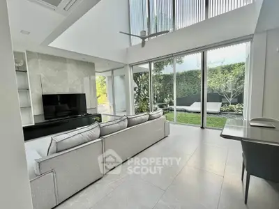 Spacious modern living room with large windows and garden view, perfect for relaxation and entertainment.