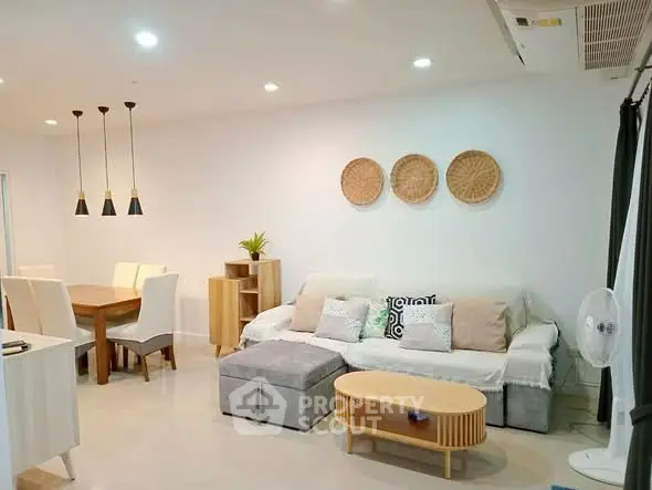 Modern living room with stylish decor and dining area, featuring cozy seating and elegant lighting.