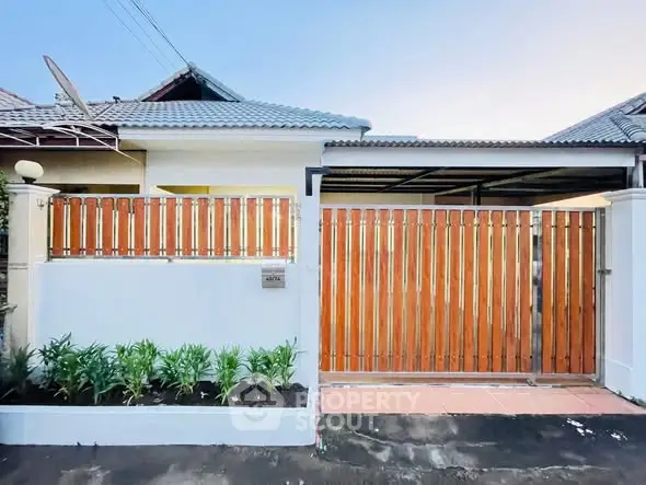 Charming single-story home with wooden gate and small garden, perfect for cozy living.