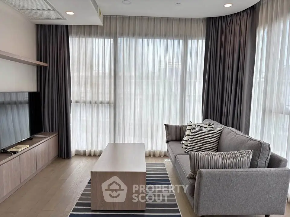 Modern living room with stylish sofa, sleek coffee table, and floor-to-ceiling windows with elegant curtains.