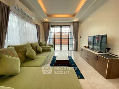 Spacious living room with modern green sofa and large TV, featuring elegant lighting and balcony access.