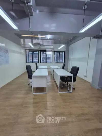 Spacious office space with modern desks and chairs, featuring large windows and ample natural light.
