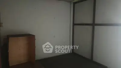 Minimalist empty room with simple wooden paneling and a small wooden cabinet.