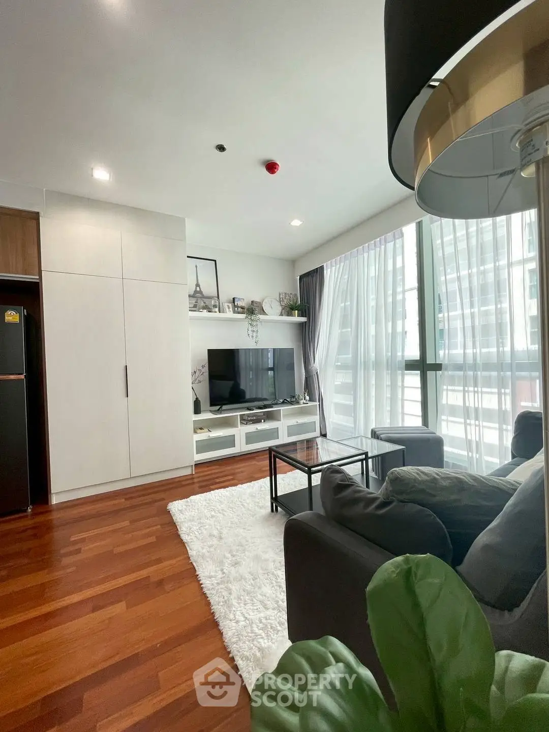 Modern living room with hardwood floors, cozy seating, and large windows in a stylish apartment.