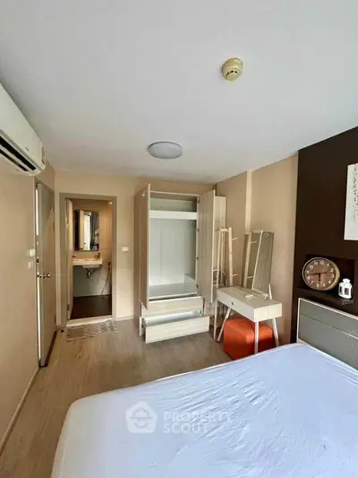 Modern bedroom with open wardrobe and ensuite bathroom in stylish apartment.