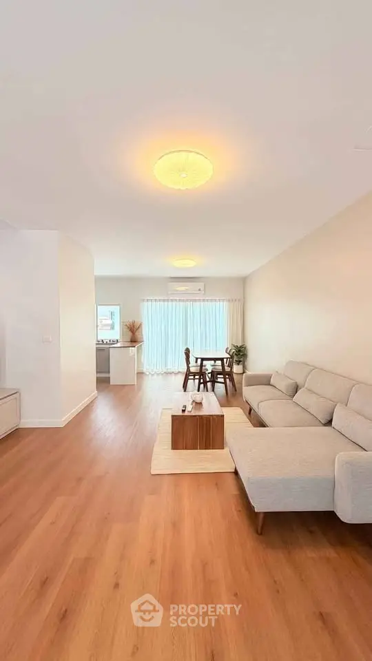 Spacious modern living room with wooden flooring and elegant furniture, perfect for family gatherings.