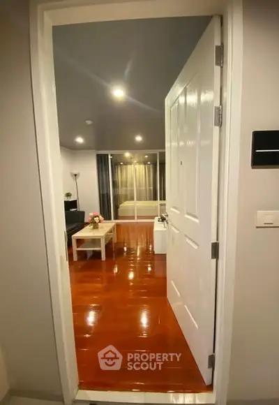 Inviting entryway leading to a cozy living room with polished wooden floors and modern decor.