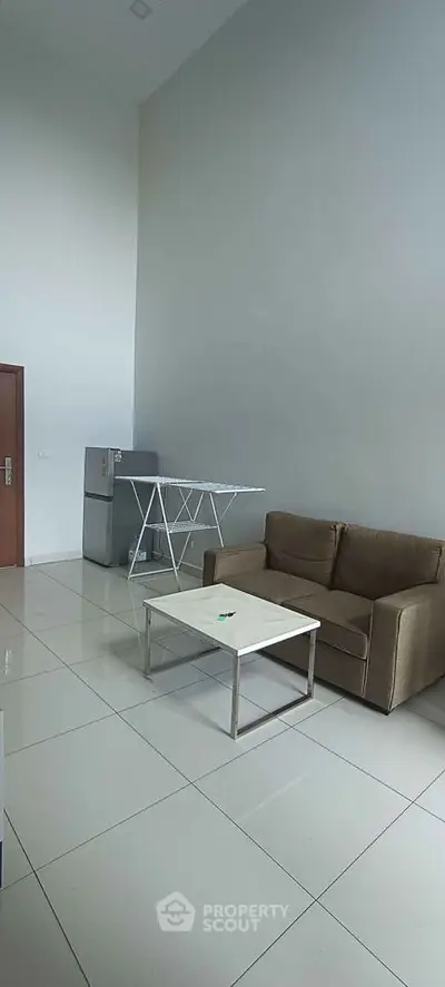 Modern living room with high ceiling, sleek sofa, and minimalist decor in a contemporary apartment.