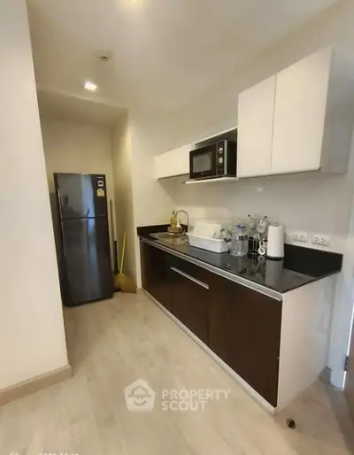 Modern kitchen with sleek cabinets and stainless steel fridge in a compact layout.