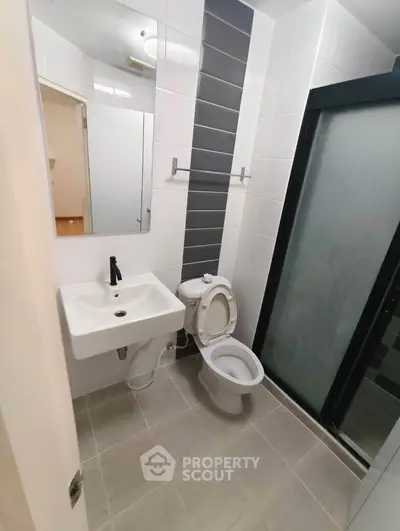 Modern bathroom with sleek design featuring a shower, toilet, and sink in a compact layout.