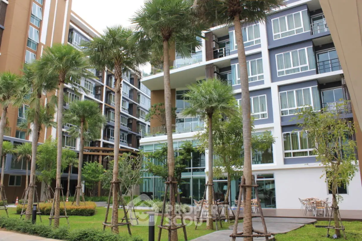 Modern condominium building with lush garden and palm trees, offering serene urban living.