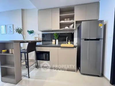 Modern kitchen with sleek cabinetry and stainless steel fridge in stylish apartment.
