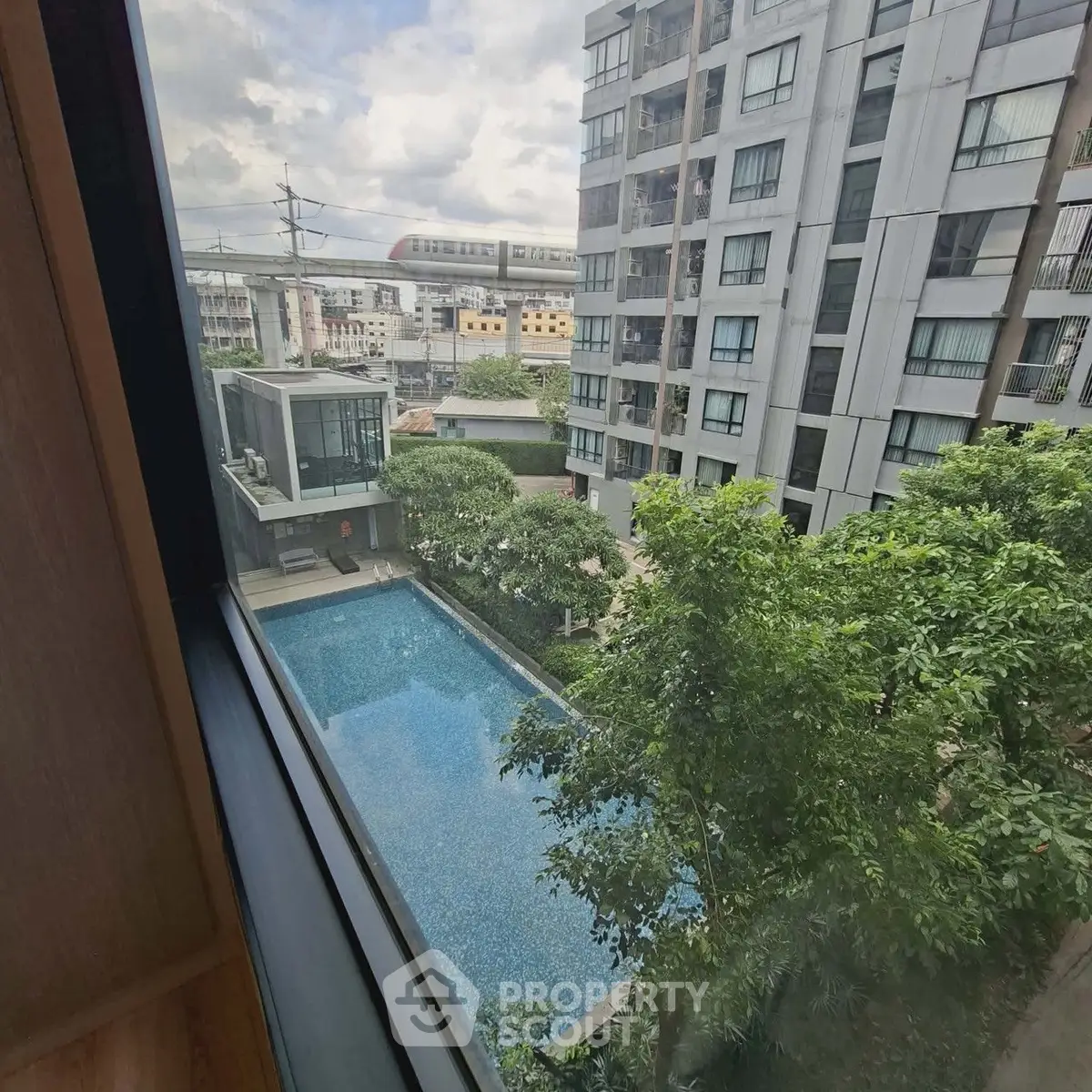 Stunning view of modern apartment complex with pool and lush greenery