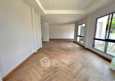 Spacious empty room with large windows and elegant wooden flooring