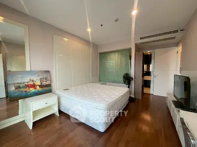 Spacious bedroom with hardwood floors, large mirror, and modern decor in a stylish apartment.